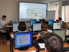 Warsztaty OpenStreetMaps w Urzędzie Statystycznym w Poznaniu. Sala komputerowa z ekranem na ścianie wyświetlającym mapę.